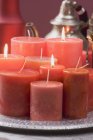 Closeup view of various red candles on tray and teapot in background — Stock Photo