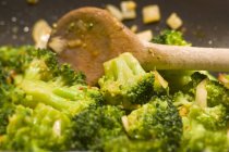 Stirring broccoli in a frying pan with a wooden spoon — Stock Photo