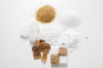 Vista superior de vários tipos de açúcar na superfície branca — Fotografia de Stock