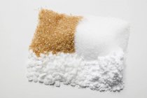 Closeup view of four different types of sugar in heaps — Stock Photo