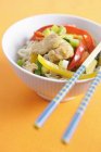 Stir-fried chicken and vegetables on noodles on white plate over orange surface — Stock Photo