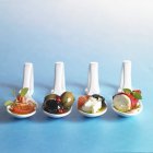 Closeup view of various antipasti on spoons in a row — Stock Photo