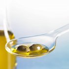 Grüne Oliven mit Öl auf Löffel — Stockfoto