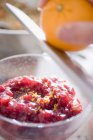 Closeup cropped view of person grating orange zest to cranberry sauce — Stock Photo