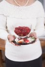 Woman holding cranberry sauce in glass bowl — Stock Photo