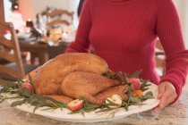 Woman holding roast turkey — Stock Photo