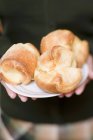 Closeup cropped view of person holding plate of popovers — Stock Photo