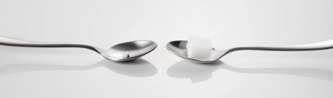 Primo piano vista di due cucchiai con dolcificante e cubetto di zucchero — Foto stock