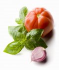 Tomato with basil and garlic clove — Stock Photo