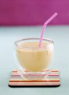 Vista ravvicinata del mango Lassi in un bicchiere con una cannuccia — Foto stock