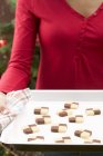 Hands holding baking tray of cookies — Stock Photo