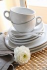 Vista de primer plano de tazas blancas con platillos y platos en pila - foto de stock
