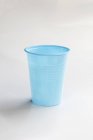 Closeup view of one blue plastic cup on white surface — Stock Photo