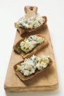 Artichokes and basil on toast on chopping board — Stock Photo
