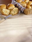 Rouleaux dans un panier et sur une assiette avec beurre et couteau — Photo de stock