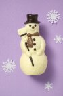 Крупный план шоколадного снеговика, окруженный бумажными снежинками — стоковое фото