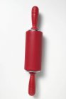 Closeup top view of one red rolling pin on white surface — Stock Photo