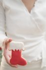 Vista cortada de mulher segurando biscoito de Natal em forma de bota vermelha — Fotografia de Stock