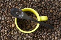 Taza de café espresso y cuchara en granos de café - foto de stock