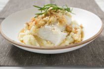 Haddock with potato crust on mashed potato on white plate — Stock Photo