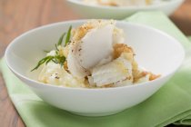 Schellfisch mit Kartoffelkruste auf Kartoffelpüree auf weißem Teller über grünem Handtuch — Stockfoto