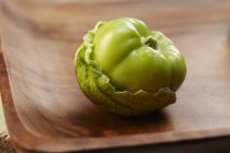 Tomatillo with husk laying on wooden plate — Stock Photo