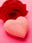 Vista close-up de coração de açúcar e rosa vermelha — Fotografia de Stock