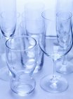 Closeup view of various empty glasses on blue surface — Stock Photo