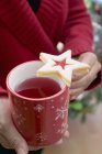 Abgeschnittene Ansicht einer Frau mit einem Becher Tee mit Marmeladenkeks — Stockfoto