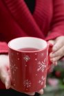 Vista da vicino della donna che tiene una tazza di tè con motivi a fiocco di neve — Foto stock