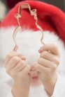 Closeup view of child in Father Christmas hat holding biscuit cutter — Stock Photo