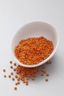 Closeup view of red lentils in a white dish and beside it — Stock Photo