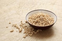 Elevated view of soy granules in bowl and on beige surface — Stock Photo