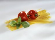 Paquete de espaguetis crudos con tomates - foto de stock