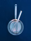 Top view of a saucepan with a whisk on blue background — Stock Photo