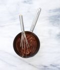 Chocolate derretido en cacerola con batidor - foto de stock