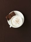Cup of coffee with milk and brownie serving — Stock Photo