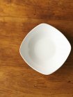 Top view of a white porcelain bowl on a wooden surface — Stock Photo