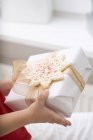 Child holding Christmas gift with star-shaped cookie — Stock Photo
