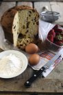 Vista de primer plano de panettone con harina, huevos y fresas - foto de stock