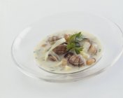 Молюски та картопляний суп у скляній тарілці на білому тлі — стокове фото