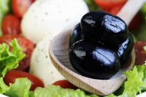 Black olives in wooden spoon — Stock Photo