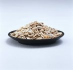 Closeup view of rolled oats on black plate — Stock Photo