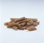 Raw brown penne pasta — Stock Photo