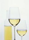 Vasos de vino blanco delante de la botella - foto de stock