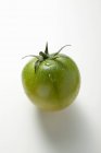 Green tomato with drops of water — Stock Photo