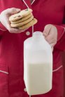 Closeup cropped view of woman holding cranberry cookies and bottle of milk — Stock Photo