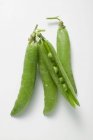 Pea pods on white surface — Stock Photo