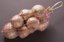 Brown onions in net — Stock Photo