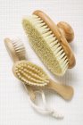 Top view of three different wooden brushes on white fabric surface — Stock Photo